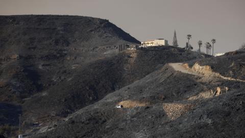 Burnt hills and a single house in the distance after wildfires through Almeria province, Spain.