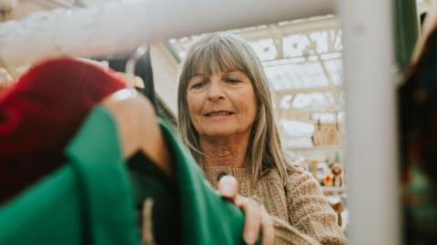 Woman looks at a rack of clothes in a market.