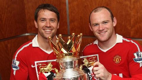 Footballers Michael Owen and Wayne Rooney, in red Manchester United kits, pose with the Premier League trophy in 2011