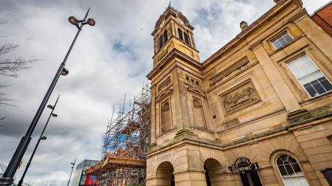 The light coloured stone of the Guildhall Theatre building with scaffolding over part of it
