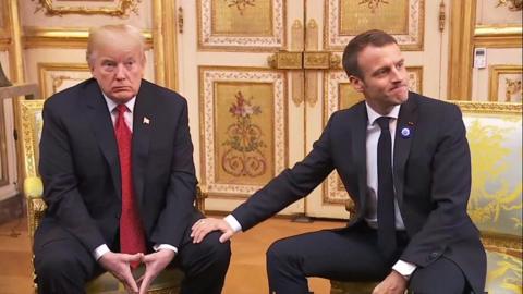 Emmanuel Macron gives US president Donald Trump an awkward leg rub on 10 November 2018