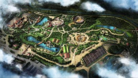 A map of how the new them park will look. It shows a large lake with a bridge running across. A circular building resembling a jousting area or colliseum and several medieval buildings.