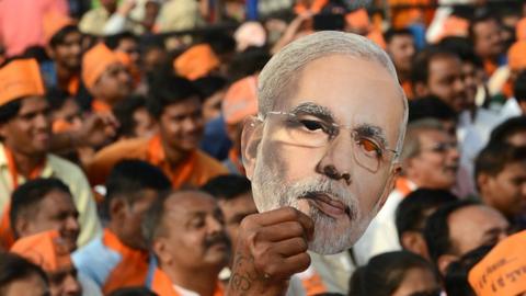 A supporter of Bhartiya Janta Party (BJP) hold a cut out of Indian Prime Minister Narendra Modi during a rally at Kalol, some 30 kms from Ahmedabad on December 8, 2017