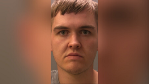 A mugshot of Callum Johnstone. He has dark blond hair with a fringe and wears a severe expression. 