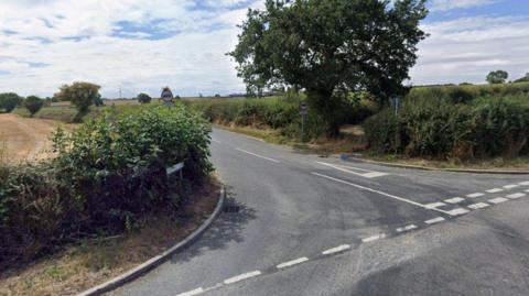 Junction of country road with hedges runing alongside it