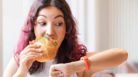 Woman eating and checking the time