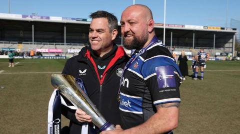 Tom Dunn (right) holding the Premiership Rugby Cup trophy with head of rugby Johann van Graan