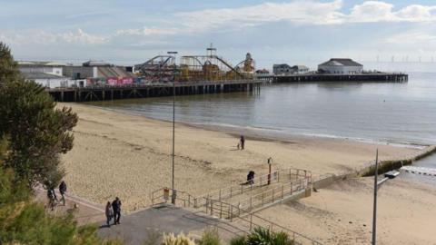 A general view of the long Clacton Pier, with its various rides and amusements on it, and the beach.