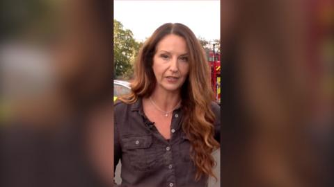 Woman with long brown hair standing in front of fire truck