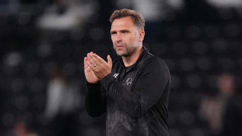 John Eustace walks on the pitch and claps his hands