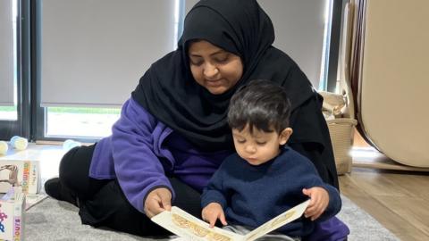 Nursery worker and toddler reading a book together