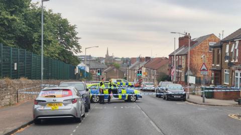 Police car with a cordon on a road with a downhill slope