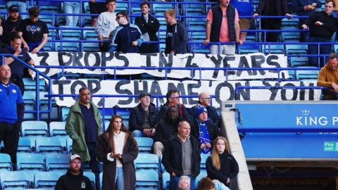 Leicester fans protest at their game against Millwall with a banner which says "3 drops in 4 years top shame on you"