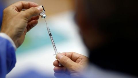 A firefighter fills a syringe with a dose of the "Comirnaty" Pfizer BioNTech COVID-19 vaccine