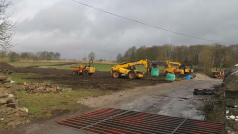 Diggers prepare fields to become a development site.