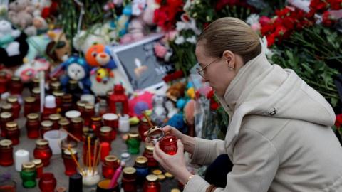 Woman kneels at memorial in Russia