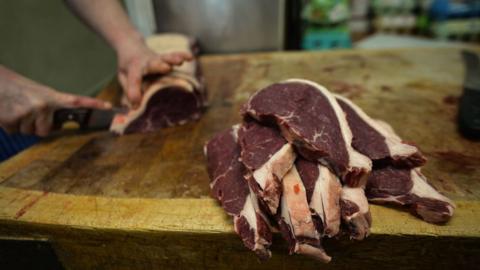 Butcher cutting a piece of beef for parts at shop in Ireland (April 2021)