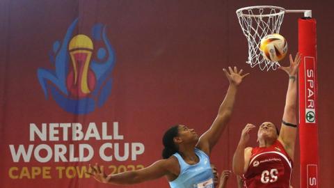 Mo'onia Gerrard of Fiji and Mali Rusivakula of Tonga challenge for possession next to the basket with tournament logo clear in the background during the Netball World Cup