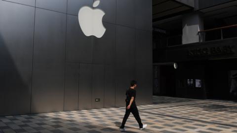 This photo taken on August 3, 2017 shows a man walking past an Apple store in Beijing.