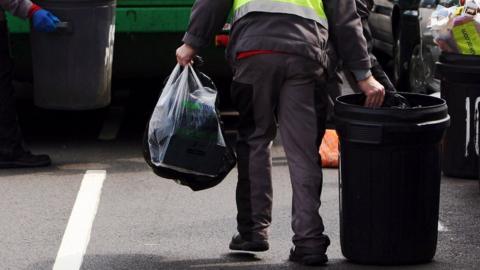 A person carrying a bin