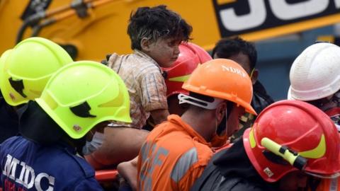 Rescue workers carry Mohammed Bangi, a four-year-old boy, after he was rescued from the rubble at the site of a collapsed five-storey building in Mahad