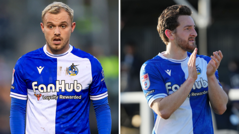 Luke Thomas (left) standing on the pitch and Tom Lockyer (right) looking to the left and clapping his hands while standing on the pitch