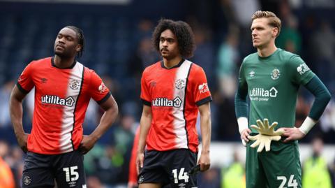 Teden Mengi, Tahith Chong and Thomas Kaminski stand on the pitch after Luton's relegation was confirmed