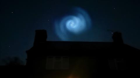 Swirling pattern in the night sky above a house.