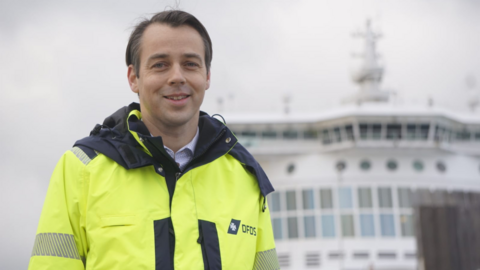 Filip Hermann is wearing a fluorescent DFDS coat while stood on the bow of a ship