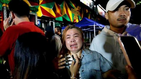 A relative of a victim in tears outside the bar in Bangkok that was hit by a fierce fire