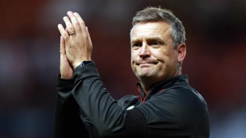 Michael Skubala holds his arms up and claps his hands at the end of Bristol City v Newcastle