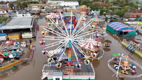 Aerial view of a flooded amusement park including a large ferris wheel.