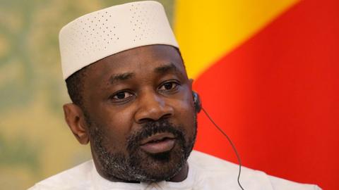 Gen Assimi Goïta is pictured wearing a white cap at top. He also wears an earpiece. 