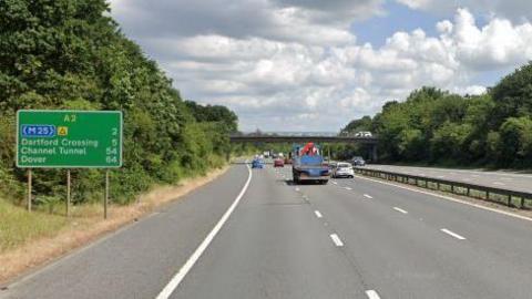 A google maps image of the A2 carriageway with vehicles driving on both sides of the road, a green sign to the left and a road bridge up ahead