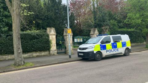 Police van outside the entrance of the cemetery 