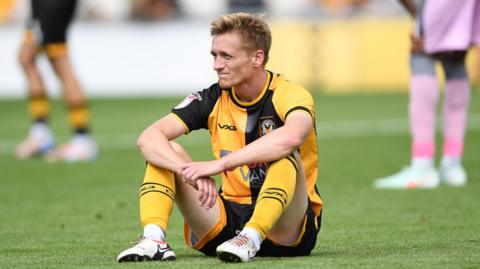 Matt Smith sat on the floor with arms crossed during a Newport County game