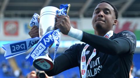 Nathan Trott holds a trophy celebrating Cardiff's promotion