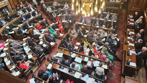 A packed Bradford Council (City Hall) council chamber showing various sets of benches.