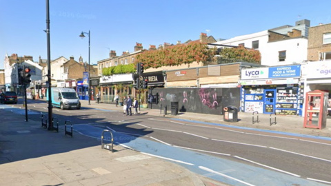 A screenshot from Google Streetview shows a view of shops on Clapham High Street, close to Tremadoc Road. The archive picture shows people crossing the street as a van waits at traffic lights