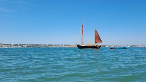 A small boat on a calm, turquoise sea with blue skies overhead.