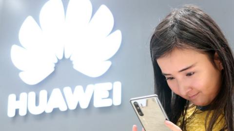 A young woman looking at a Huawei smartphone