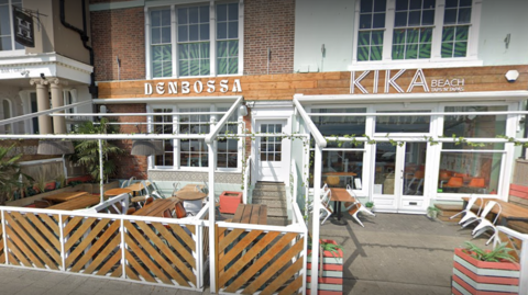 An exterior scene of the deserted Kika Beach bar with wooden outside seating