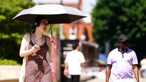 A person uses an umbrella to cover from the sun in Birmingham on 26 May 2026.