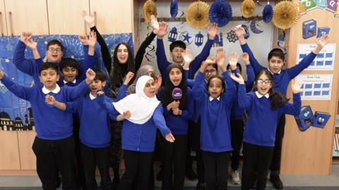A group of kids raising their arms, as they should "Eid Mubrak!"
