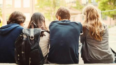 Stock image of the backs of four young people 