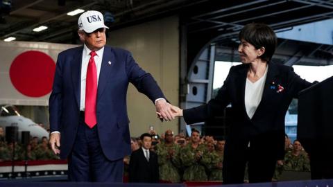 U.S. President Donald Trump leads Japanese Prime Minister Sanae Takaichi off the stage after speaking to troops aboard USS George Washington at Fleet Activities Yokosuka on October 28, 2025 in Yokosuka, Japan. Trump is visiting Japan, fresh off an appearance at the ASEAN summit in Malaysia, and will next travel to South Korea for the APEC meetings.
