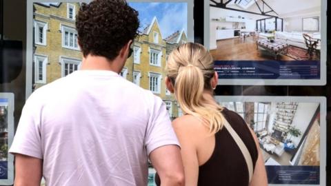 Couple looking in estate agent's window