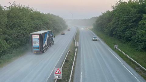 A view of the A6 near Mountsorrel, Leicestershire, taken from a bridge with a haze towards the sky 