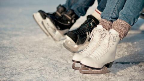 A stock picture of pairs of ice skates on an ice rink.