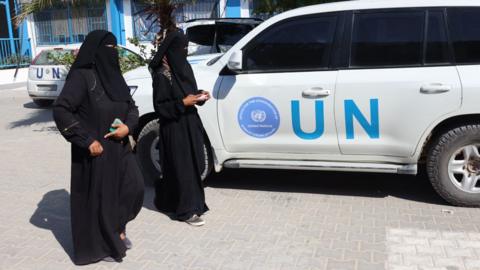 Palestinian women walk past a UN vehicles at the UNRWA Japanese Health Center in Khan Yunis on the southern Gaza Strip